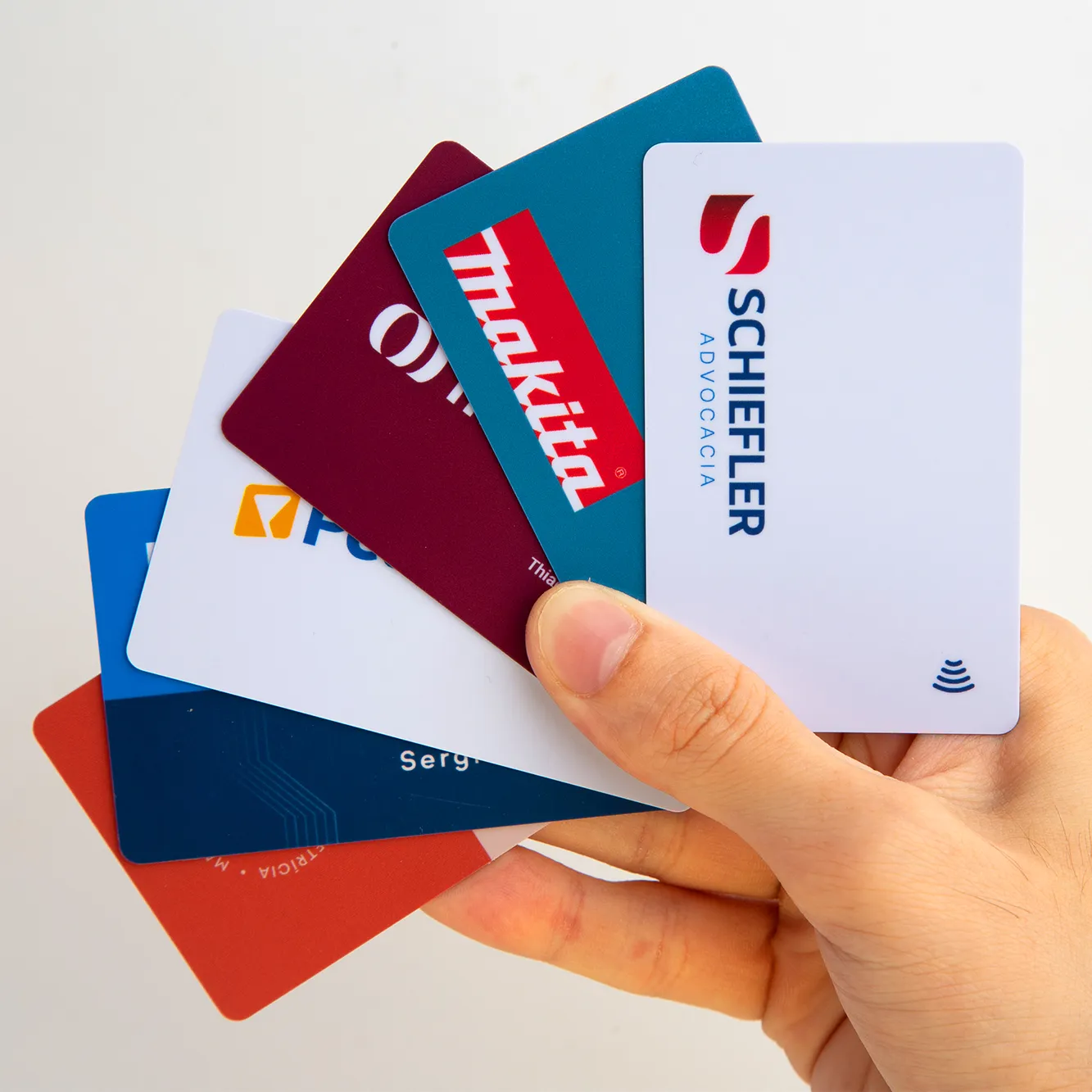 Pessoa segurando diferentes cartões de visitas com tag NFC desenvolvidos para empresas